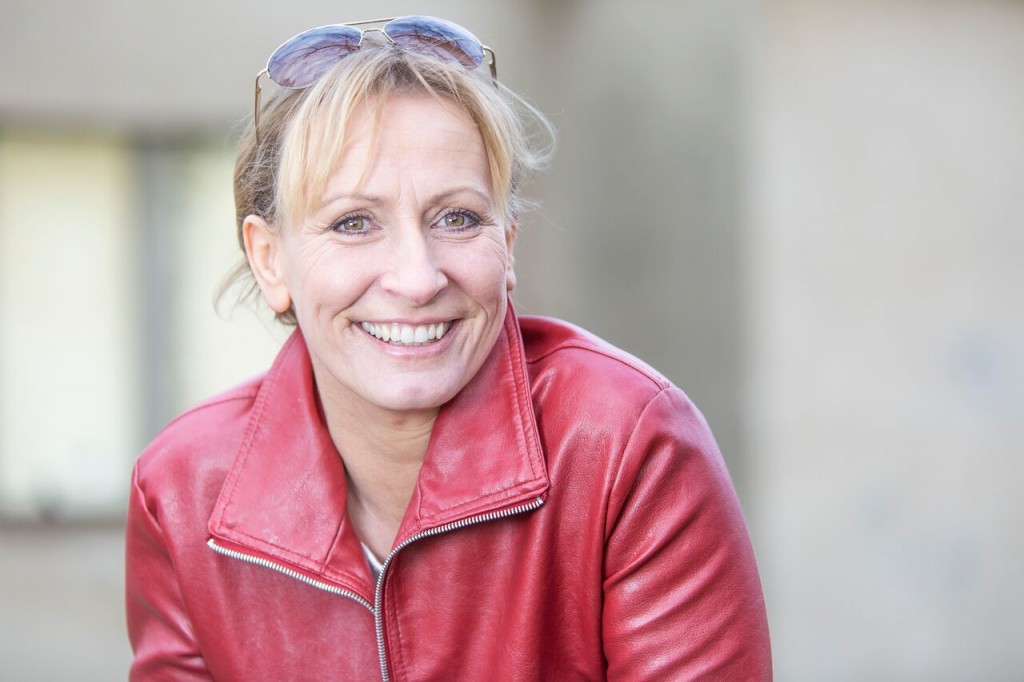 Ulla Wagener lächelt in die Kamera, rote Lederjacke, Sonnenbrille im Haar